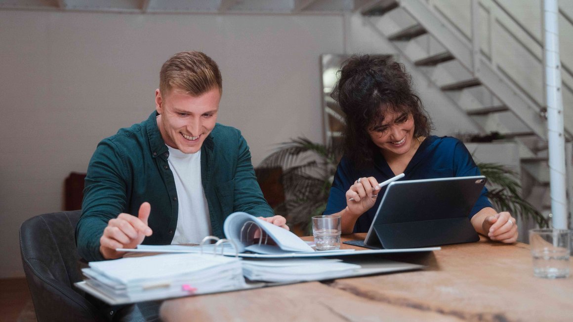 Comment se libérer de ses dettes Un jeune couple est assis ensemble et tient un livre de comptes.