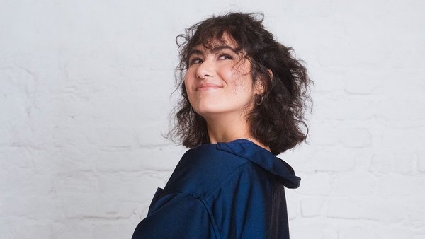 Funktioniert die 50-30-20-Regel auch mit wenig Lohn? Frau mit blauem Hemd und braunen Haaren schaut verschmitzt nach oben.