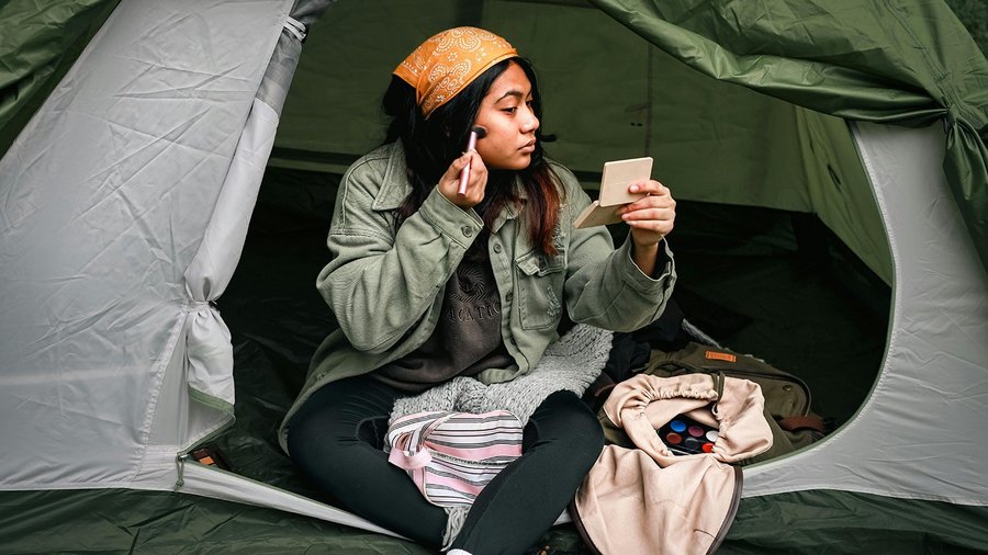 Une femme est assise dans une tente et se maquille