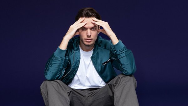 Was sind Konsumkredite? Junger Mann sitzt auf dem Boden und hält sich besorgt die Hände an den Kopf
