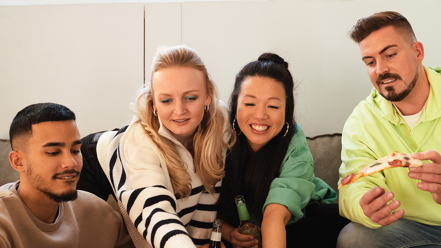 Comment fonctionne une colocation ? Quatre jeunes gens sont assis ensemble sur un canape et rient