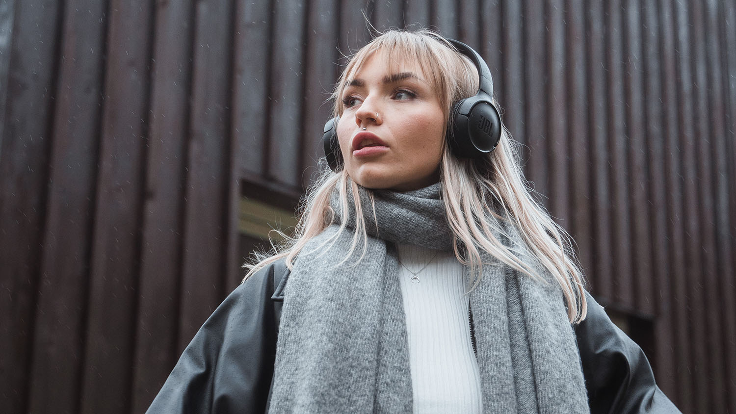 Vermögensaufbau mit wenig Geld: Das Wichtigste zuerst Junge Frau mit Kopfhörern guckt in die Ferne